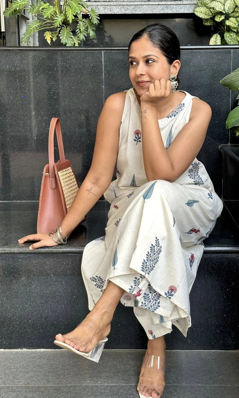 Woman in a floral saree sitting on steps with a pink handbag.